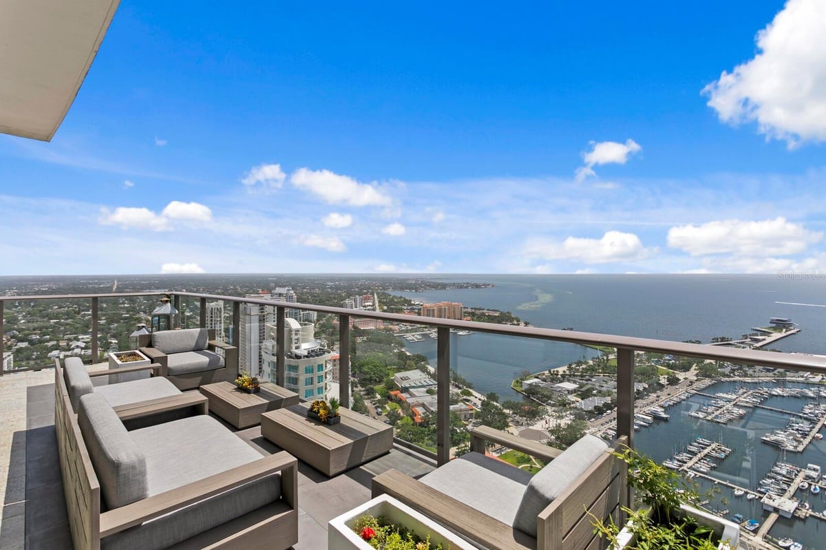 Balcony view with outdoor seating overlooking the ocean and city skyline